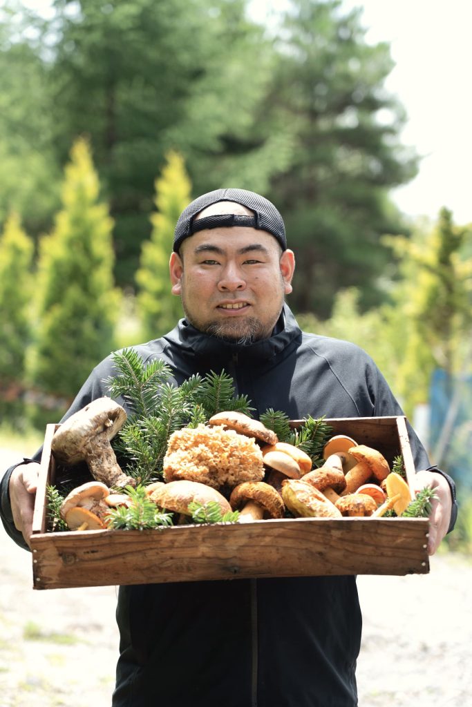 キノコがたくさん入った箱を抱える男性